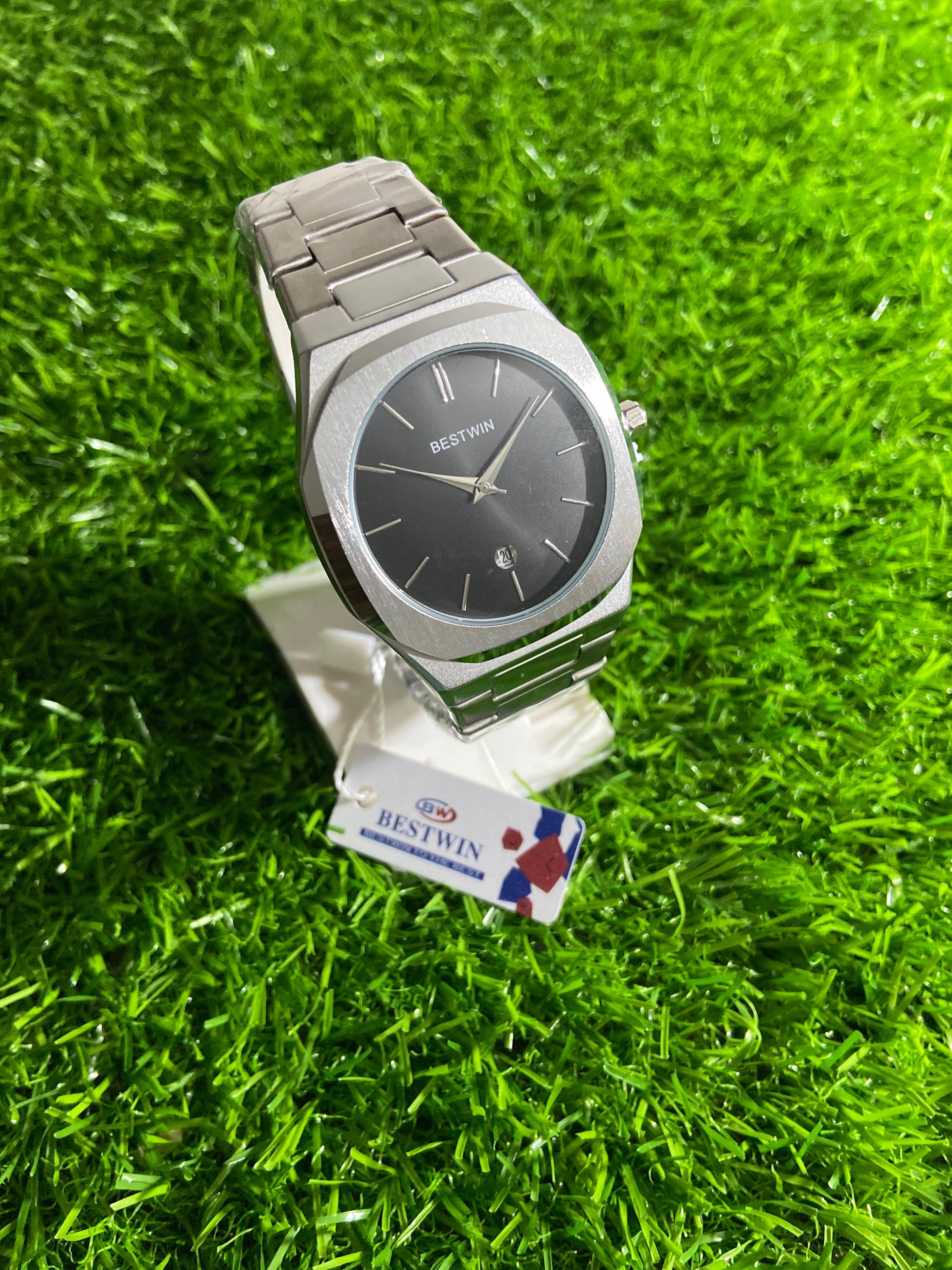 Silver watch on a stand with a green grass background
